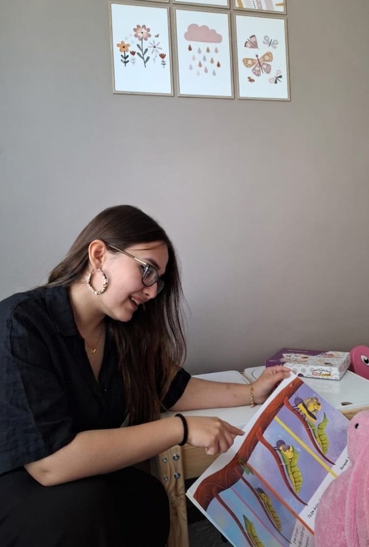 Dkt. Ayşe Türedi, terapi odasında resimli kitapla oyun temelli dil çalışması yaparken